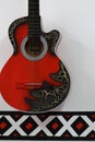 A red and black guitar hanging from a white wall