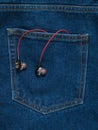 Red with black headphones sticking out of the pocket of blue jeans Royalty Free Stock Photo