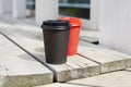 Red and black paper cups of coffee to takeaway on wooden floor outside the cafe. Breakfast morning on air. Royalty Free Stock Photo