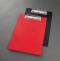 Red and black plastic clipboard on gray background.