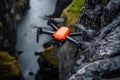 A small orange drone flying over a rocky cliff Royalty Free Stock Photo