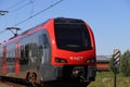 Red and black R-net train at a railroad crossing in Waddinxveen between Alphen aan den Rijn and Gouda