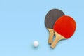 Red and black rackets for table tennis with white ball on blue background. Ping pong sports equipment in minimal style. Flat lay, Royalty Free Stock Photo