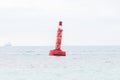 Red and black steel navigational floating buoy - West cardinal mark in blue, bright sunlight.