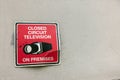 red black white broken old sign closed circuit television on premises warning with camera icon