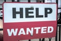 A red black and white sign with help wanted text hanging on a black cast iron fence along the sidewalk with two bolts in Chicago Royalty Free Stock Photo