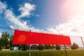 Red blank advertising banner hanging on a fence against the blue sky on a sunny day