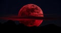 Red Blood Moon rises dramatically over dark mountains Royalty Free Stock Photo