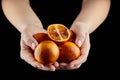 Person holging handful of half and whole red or blood oranges on black background