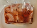 red bloody meat thawing in a plastic bag in water