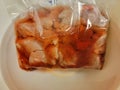 red bloody meat thawing in a plastic bag in water