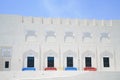 Red and blue bench seats outide white building with Arabic or Islamic design details