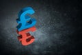 Red and Blue British Currency Symbol or Sign With Mirror Reflection on Dark Dusty Background