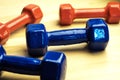 Red and blue dumbbells for fitness at home, chaotically scattered on wooden surface, wooden background