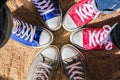 Red, blue and gray sneakers standing in the circle on dry sand, view from above . Friendship, fashion, lifestyle and adventure con Royalty Free Stock Photo