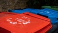 Red, blue and green recycling trash cans in a garden with instructions written