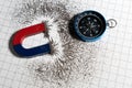 Red and blue horseshoe magnet or physics magnetic and compass with iron powder magnetic field on white paper graph background. Royalty Free Stock Photo
