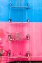 Red and blue metal rungs of a ladder going up the side of a train Royalty Free Stock Photo