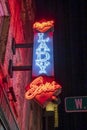 A red and blue neon sign on tops of The Lady and Sons restaurant on Congress Street at night surrounded by buildings