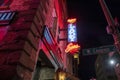 A red and blue neon sign on tops of The Lady and Sons restaurant on Congress Street at night surrounded by buildings