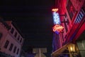 A red and blue neon sign on tops of The Lady and Sons restaurant on Congress Street at night surrounded by buildings