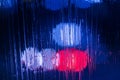 An abstract background of red and blue police lights bokeh trough wet glass at night close-up with selective focus Royalty Free Stock Photo