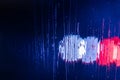An abstract background of red and blue police lights bokeh trough wet glass at night close-up with selective focus Royalty Free Stock Photo