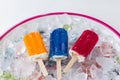 Red and blue and orange popsicle lying on ice in a tray. Royalty Free Stock Photo