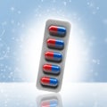 Red and blue pills in a blister on bokeh background