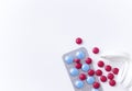 Red and blue pills on white background. Scattered red tablets from a plastic jar next to blue tablets in blisters. Royalty Free Stock Photo