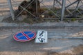 Red and blue road sign prohibiting the stopping of a vehicle with a plate about the work of a tow truck lies fallen on the roadway