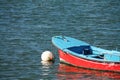 Red blue row boat parked in harbor on buoy in atlantic ocean Royalty Free Stock Photo