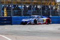 Red and blue supercar racing at a street circuit during Grand Prix with fans watching