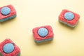 Red and blue tablets for dishwashing machine. Detergents for home hygiene. Dishwasher capsules on yellow background Royalty Free Stock Photo