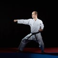 On a red and blue tatami, an active athlete does formal karate exercises