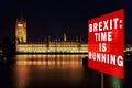 Red board with phrase & x27;Brexit: Time is running& x27;. Brexit Concept with parliament in background at night. London, UK