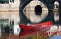 Red boat in ancient autumn lake. Stone bridge.