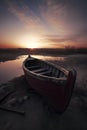 red boat on a beach at sunrise, with the sun casting a beautiful orange and pink glow in the sky, ai generative Royalty Free Stock Photo