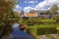 Red Boat On The Calm Water Of A Canal And Traditional Wooden Buildings In Marken, Holland