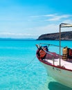 Red boat on crystal clear ocean with life vests hanging and mountain on the back