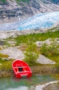 Red boat on Nigard Lake. Blue ice of Nigardsbreen glacier on background. Western Norway