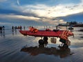 A red boat standing on the sea beach waiting for customer with a reflection on the beach