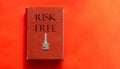 Red book with text Risk Free and a key on a red background