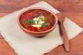 Red borscht in bowl and wooden spoon on rustic table Royalty Free Stock Photo