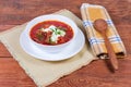 Red borscht in bowl and wooden spoon on rustic table Royalty Free Stock Photo