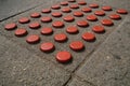 Red bottle caps arranged in a pattern on a concrete surface in an urban setting Royalty Free Stock Photo