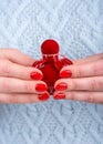 Red bottle of perfume in female hands with manicure. Royalty Free Stock Photo