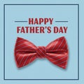 A red bow tie with diagonal white stripes is centered on a light blue background Royalty Free Stock Photo