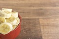 Red bowl with banana slices on wooden background Royalty Free Stock Photo