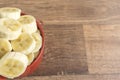 Red bowl with banana slices on wooden background Royalty Free Stock Photo